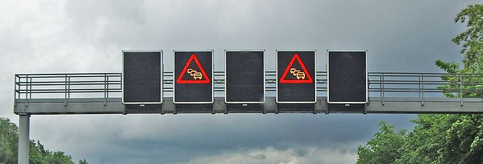 Verkehrsbeeinflussungsanlage über eine Autobahn mit angezeigter Stauwarnung