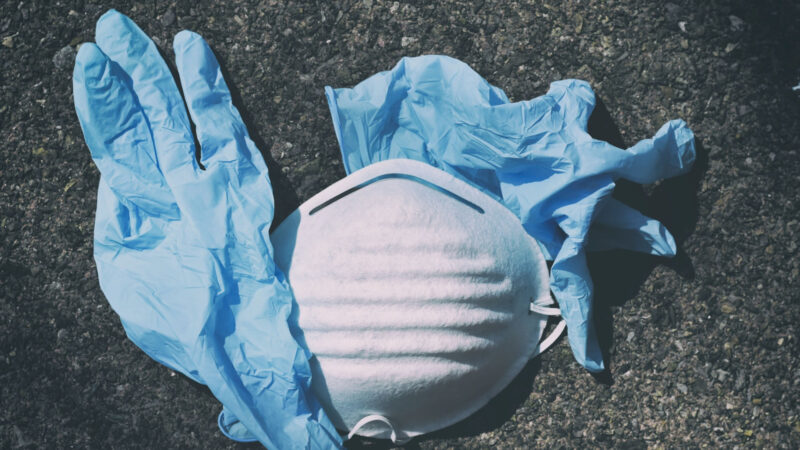 Auf dem Boden liegen 2 blaue Einmalhandschuhe (vermutlich aus Nitril) sowie eine weiße Atemschutzmaske